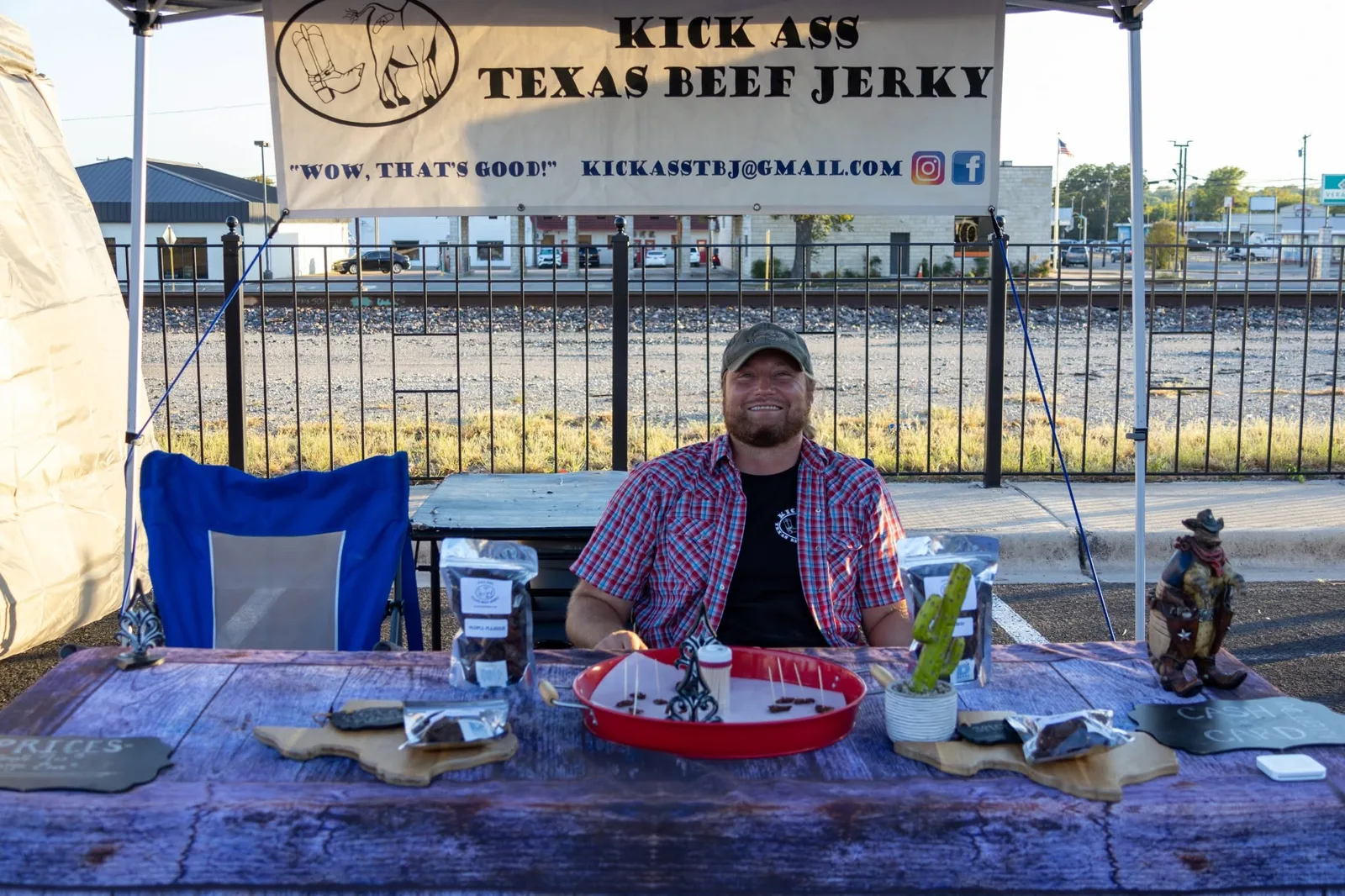 Brandon Gillespie smiling at the Kick Ass Texas Beef Jerky farmers market booth